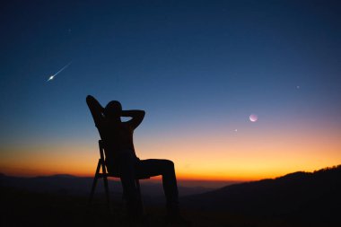 Man looking at the night sky, stars, planets, Moon and shooting stars.