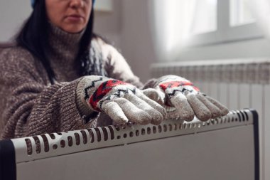 Soğuk bir kış gününde, ceketli, kazaklı ve eldivenli bir kadın. Enerji ve gaz krizi, soğuk oda, ısıtma sorunları..