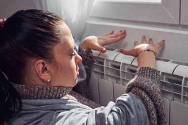 Woman indoors on a chilly winter day, energy and gas crisis, cold room, heating problems.