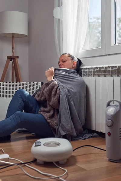 Woman indoors on a chilly winter day, energy and gas crisis, cold room, heating problems.