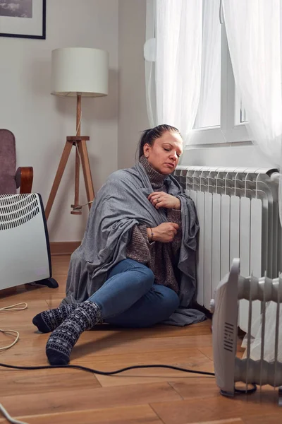 Woman indoors on a chilly winter day, energy and gas crisis, cold room, heating problems.