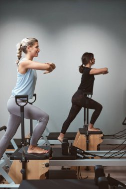 Young women exercising in a gym on pilates machines.