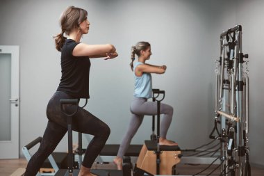 Young women exercising in a gym on pilates machines.