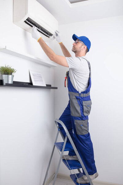Service guy cleaning and maintaining air condition unit.