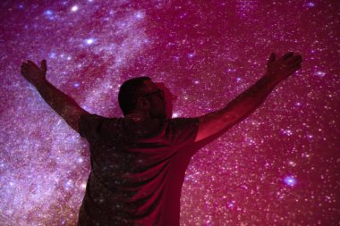 Samanyolu yıldızlı gökyüzüne sahip bir adamın silueti.