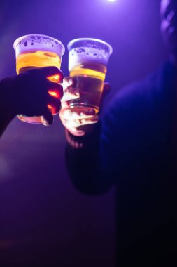 Kadın ve erkek, gece kulübünde plastik bir bardak birayla tezahürat yapıyorlar..