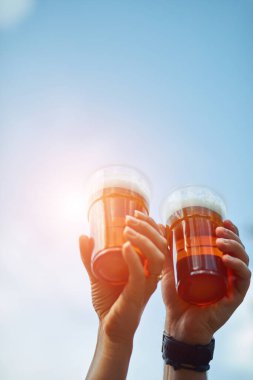 İnsanlar ellerinde bira bardakları tutarak yaz tatilinin tadını çıkarıyorlar..