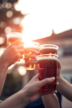 İnsanlar ellerinde bira bardakları tutarak yaz tatilinin tadını çıkarıyorlar..