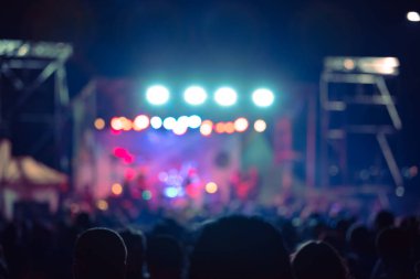 Sahne ışıkları olan, bulanık fotoğraflı konser kalabalığının siluetleri.