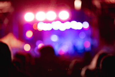 Sahne ışıkları olan, bulanık fotoğraflı konser kalabalığının siluetleri.