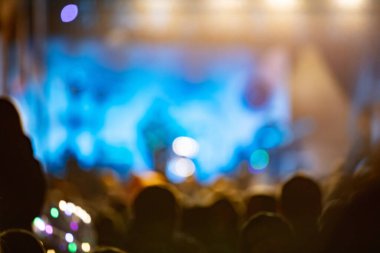Sahne ışıkları olan, bulanık fotoğraflı konser kalabalığının siluetleri.