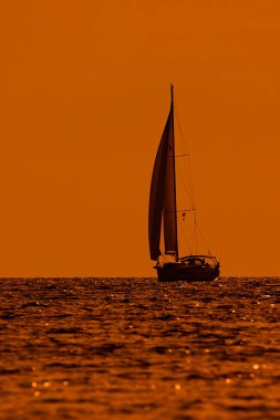 Gün batımında, gün doğumunda ve okyanus ufkunda bir yelkenlinin silueti.