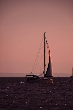 Gün batımında, gün doğumunda ve okyanus ufkunda bir yelkenlinin silueti.