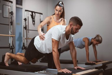 Genç kadınlar ve erkek spor salonunda kişisel antrenörleriyle egzersiz yapıyorlar..
