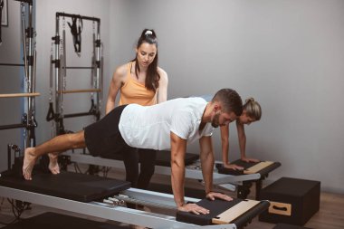 Genç kadınlar ve erkek spor salonunda kişisel antrenörleriyle egzersiz yapıyorlar..