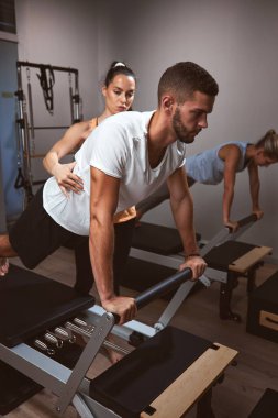 Genç kadınlar ve erkek spor salonunda kişisel antrenörleriyle egzersiz yapıyorlar..