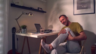 Dizi, bacağı ve eklem ağrısı olan bir adam..