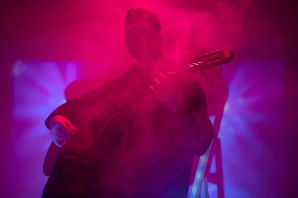 音楽家がカラフルなライトで霧のクラブでアコースティックギターを演奏 — ストック写真