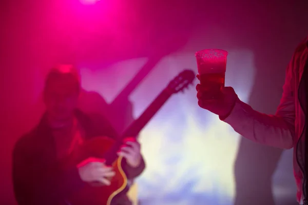 クラブでギターを弾くミュージシャンとプラスチック製のビアカップを持っている女性 — ストック写真