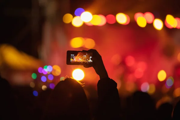 Person Mit Smartphone Und Silhouetten Von Konzertbesuchern Mit Bühnenbeleuchtung — Stockfoto