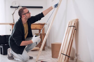 Yeni ahşap bir raf ve mobilya monte eden bir adam..