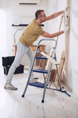 Yeni ahşap bir raf ve mobilya monte eden bir adam..