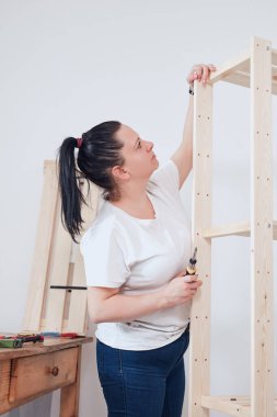 Yeni ahşap raf ve mobilyaları bir araya getiren kadın..