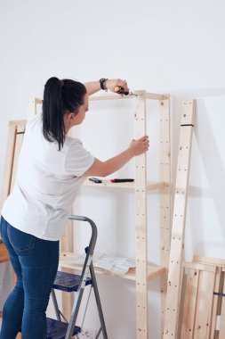 Yeni ahşap raf ve mobilyaları bir araya getiren kadın..