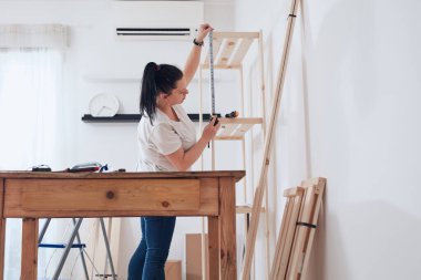 Yeni ahşap raf ve mobilyaları bir araya getiren kadın..