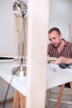 Yeni ahşap bir raf ve mobilya monte eden bir adam..