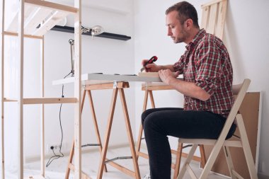 Yeni ahşap bir raf ve mobilya monte eden bir adam..