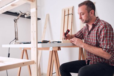 Yeni ahşap bir raf ve mobilya monte eden bir adam..