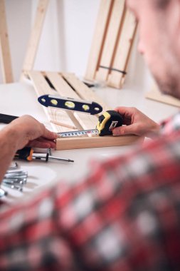 Yeni ahşap bir raf ve mobilya monte eden bir adam..