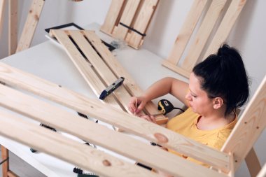 Yeni ahşap raf ve mobilyaları bir araya getiren kadın..