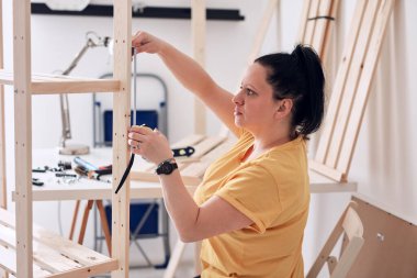 Yeni ahşap raf ve mobilyaları bir araya getiren kadın..