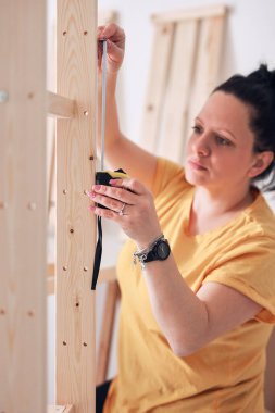 Yeni ahşap raf ve mobilyaları bir araya getiren kadın..