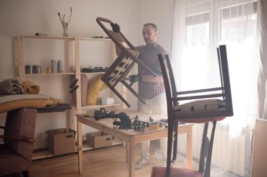 Mobilya onarımı ve restorasyonu için küçük bir ev atölyesinde çalışan bir adam.