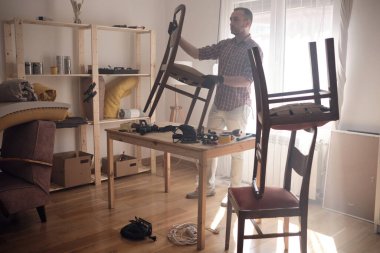 Mobilya onarımı ve restorasyonu için küçük bir ev atölyesinde çalışan bir adam.