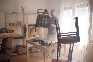 Mobilya onarımı ve restorasyonu için küçük bir ev atölyesinde çalışan bir adam.