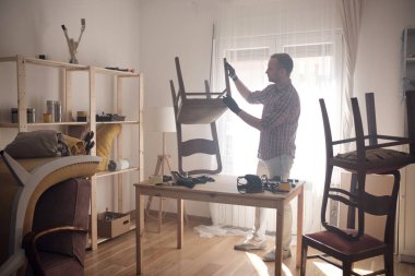 Mobilya onarımı ve restorasyonu için küçük bir ev atölyesinde çalışan bir adam.