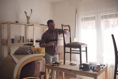 Mobilya onarımı ve restorasyonu için küçük bir ev atölyesinde çalışan bir adam.