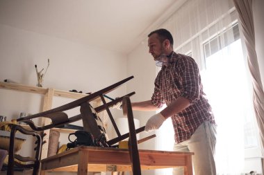 Mobilya onarımı ve restorasyonu için küçük bir ev atölyesinde çalışan bir adam.