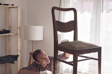 Mobilya onarımı ve restorasyonu için küçük bir ev atölyesinde çalışan bir adam.