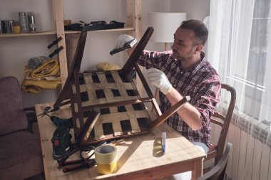 Mobilya onarımı ve restorasyonu için küçük bir ev atölyesinde çalışan bir adam.