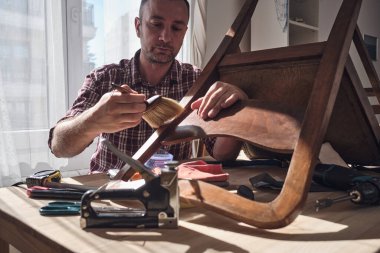 Mobilya onarımı ve restorasyonu için küçük bir ev atölyesinde çalışan bir adam.