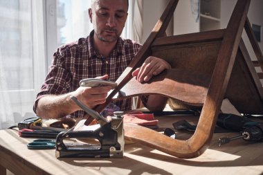 Mobilya onarımı ve restorasyonu için küçük bir ev atölyesinde çalışan bir adam.