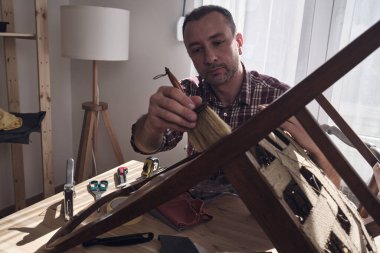 Mobilya onarımı ve restorasyonu için küçük bir ev atölyesinde çalışan bir adam.