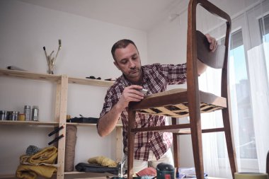 Mobilya onarımı ve restorasyonu için küçük bir ev atölyesinde çalışan bir adam.