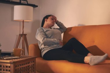 Midesi ve başı ağrıyan bir kadın..