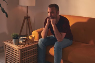 Uyuşukluk ve ilgisizlikle sıkılmış adam evde tek başına oturuyor..